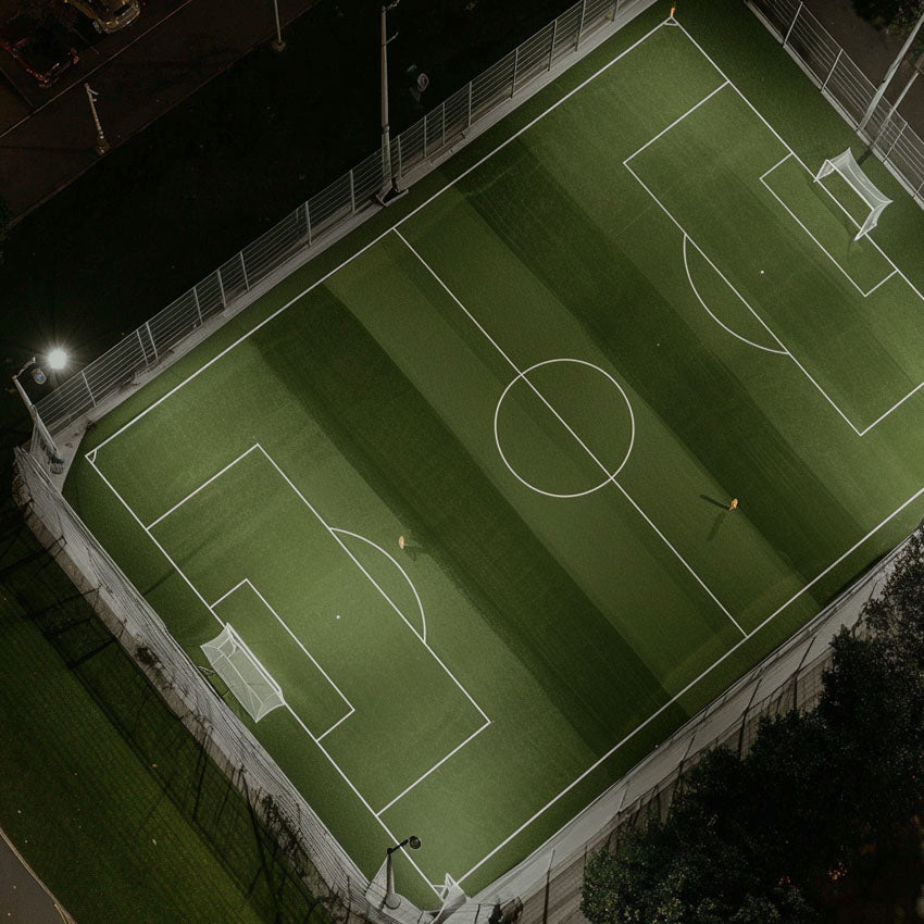 Modern 4G football pitch illuminated at night with energy-efficient LED floodlights, designed for performance and minimal glare.