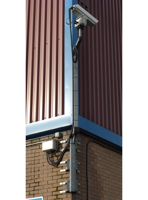 Wall-mounted square CCTV camera pole with corner bracket for secure surveillance installation on industrial buildings and commercial property exteriors.