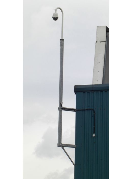 Wall-mounted CCTV camera pole with corner bracket and galvanised finish, ideal for building perimeter surveillance and security camera installations.